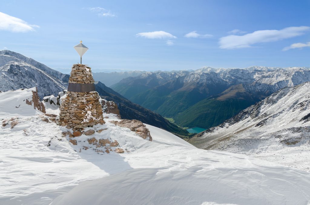 Die Auffundstelle von Ötzi im Sonnenschein. Die Steinpyramide auf 3200 Metern mit Blick in das Schnalstal und auf den Stausee
