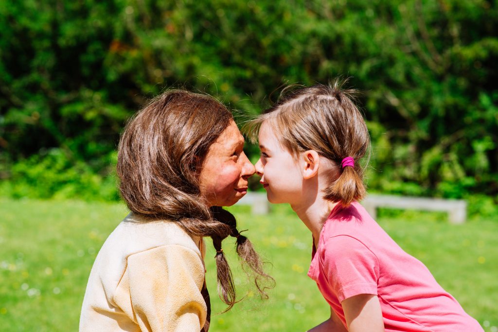Die Figur des Neandertalerrmädchens Kina, die nach einem 65.000 Jahre alten Kinderschädel nachempfunden wurde, schaut einem Mädchen der Jetztzeit in die Augen.