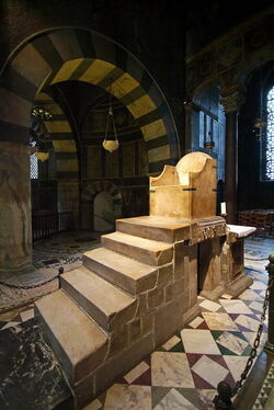 Der steinere Thron von Karl dem Großen im Aachener Dom. Eine steinerne Treppe führt zu ihm hinauf.