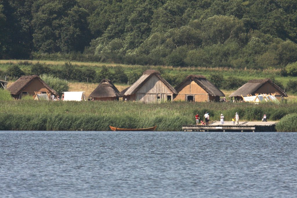 Die Wikingersiedlung Haithabu bei Schleswig. Das Bild ist von der Schlei aus aufgenommen und zeitgt die Reetdachdächer der originalgetreu aufgebauten Langhäuser der Wikinger