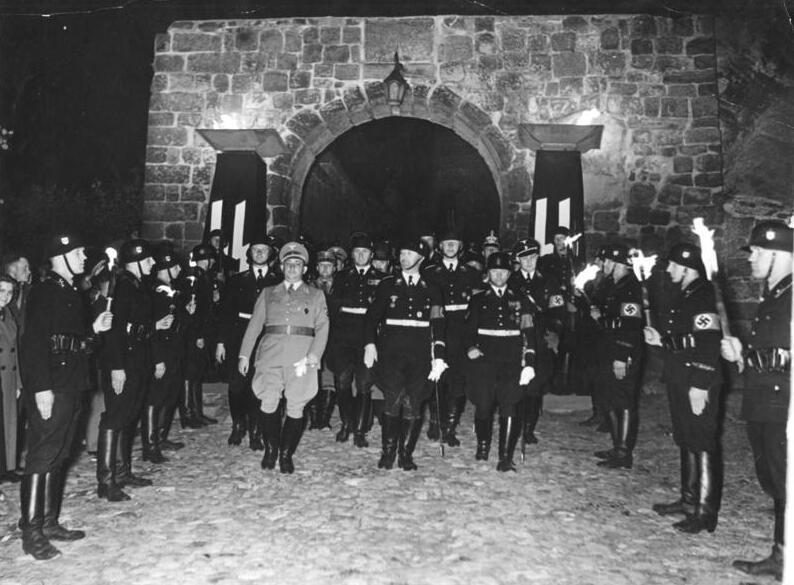 Historisches Foto von der Heinrichsfeier der Nationalsozialisten in Quedlinburg. Heinrich Himmler verlässt von die Stiftskirche in Quedlinburg. Von SS Größen begleitet schreitet er duch ein Spalier von Fackelträgern.