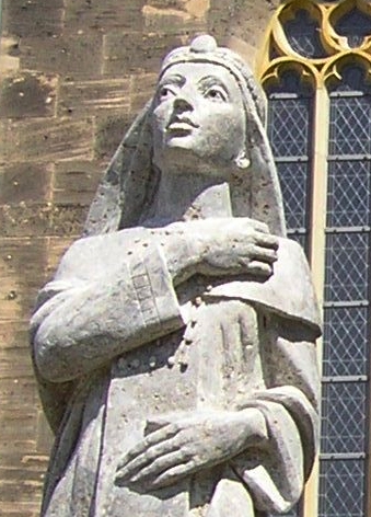 Weibliche Steinfigur in scheinbar religiöser Tracht mit Kopfbedeckung schaut in den Himmel. Sie steht in Eschwege in Hessen und stellt Kaiserin Theophanu dar.